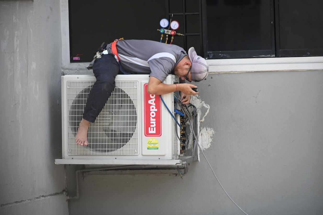 Technicien installant une unité extérieure de climatisation réversible à Biarritz